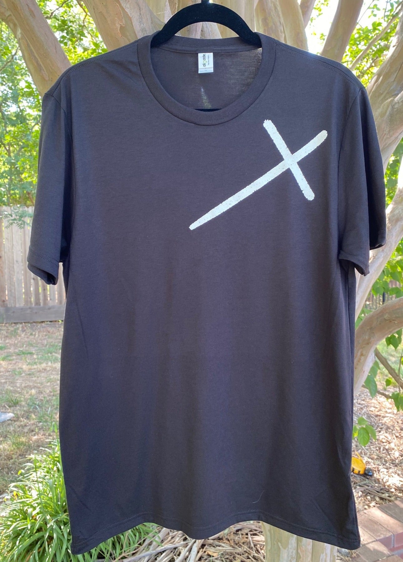 Black tee with a cross on the front left chest and "Jesus Has My Back" printed on the back shoulder. All print is in white. 