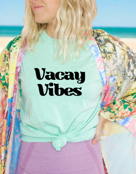 Mint green t-shirt with Vacay Vibes printed on the front in black. Vacay on the top and Vibes underneath.
