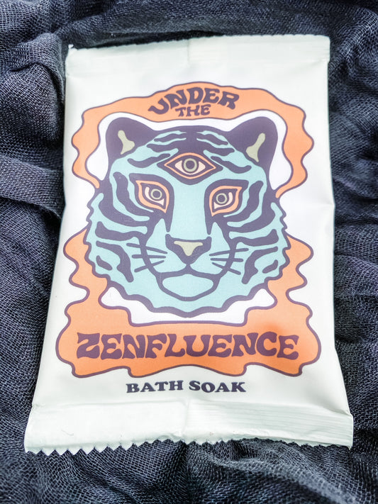 Light green package of bath salts with a tiger on the front with a third eye and "Under the Zenfluence Bath Soak" written on the front. 